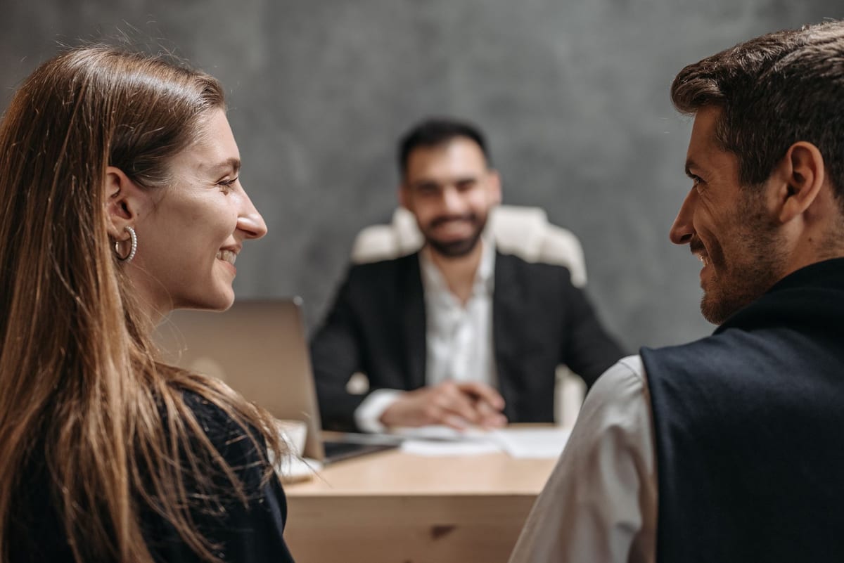 A couple smiling at each other during a meeting with a lawyer
